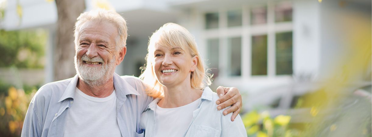 couple smiling in front of home